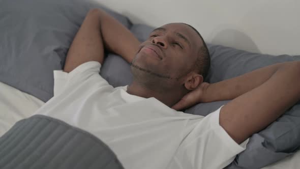 African Man Laying in Bed Awake Thinking