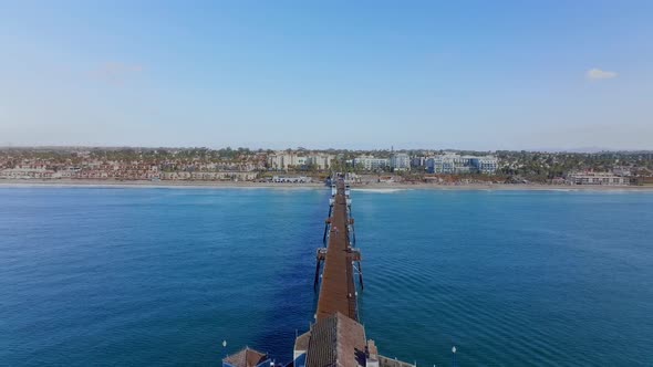 Extensive old wooden pier on Oceanside coastline, California, USA. drone reverse shot