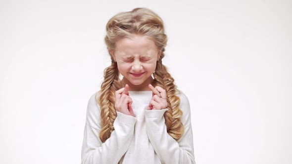 Young Caucasian Beautiful Girl with Long Blonde Hair Standing with Closed Eyes and Crossed Fingers