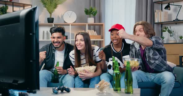 Male and Female Football Fans Celebrating Goal with High Five During Revision Match on TV at Home