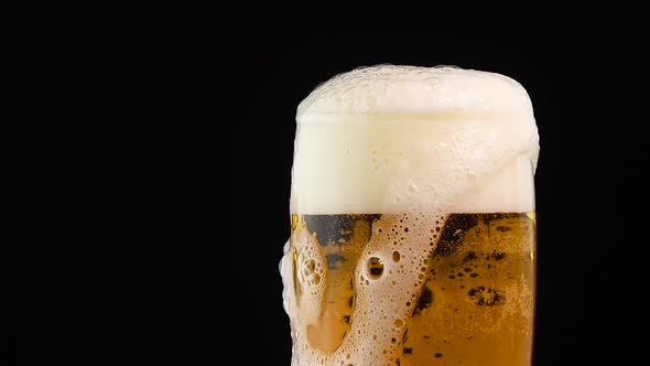 Pouring lager beer in big glass over black background