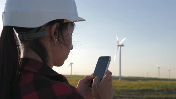 Woman Engineer Working in Wind Turbine Electricity Industrial at Sunset.