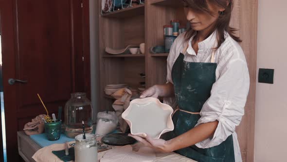 Professional Potter Decorating and Painting a Dish After She Has Baked It in the Kiln