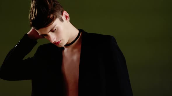 Androgynous man in blazer posing against black background