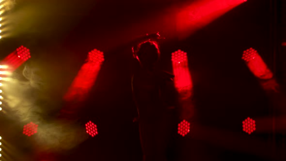 Silhouette of Dancing Young Women on Stage in a Dark Studio with Smoke and Neon Lighting. Red Neon