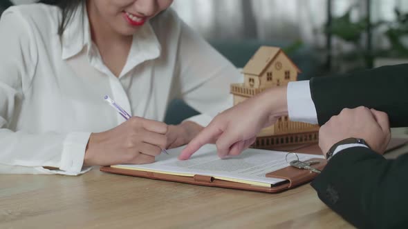 Close Up Of A Woman With Real Estate Agent Signing On House Purchase Contract Paper
