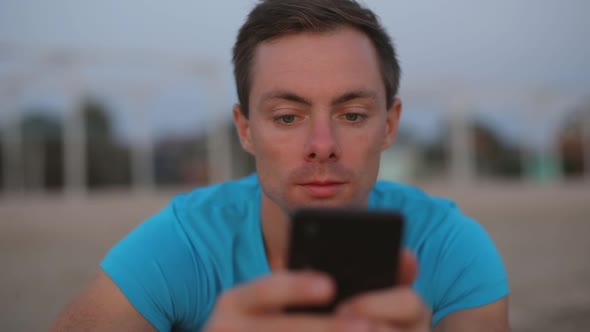 Man Using Smartphone Sitting on the Beach