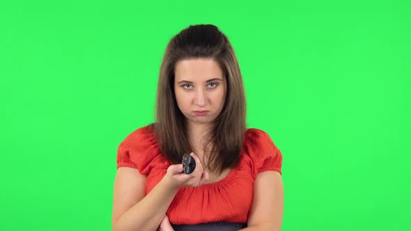Portrait of Cute Girl with TV Remote in Her Hands, Switching on TV. Green Screen