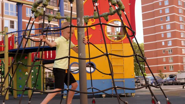 A Little Cheerful Boy is Spinning on a Modern Carousel on the Playground