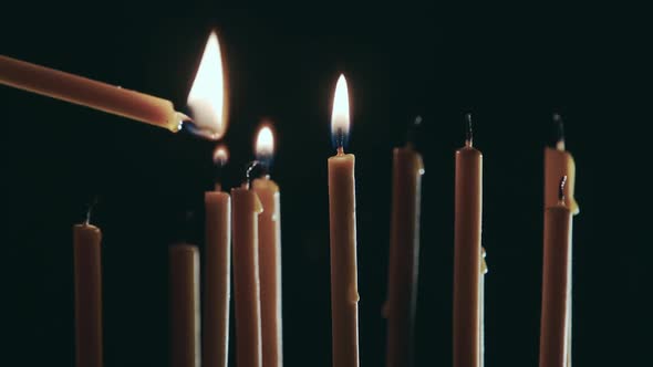 Person Sets a Candle in the Temple. Black Background