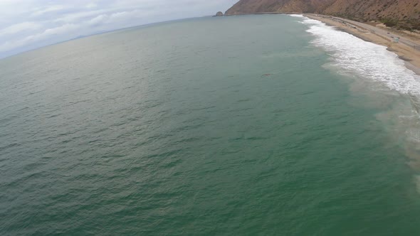 Flying Over Pacific Ocean, Peaceful Blue Green Waves and Cars Moving in Background