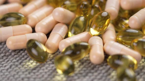 Mix of capsules of vitamin B complex and omega 3 pills close-up on a gray rough cloth