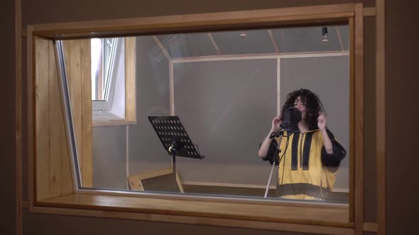 Young Modern Woman Singer is Recording a Song in a Recording Studio