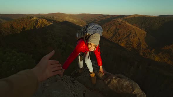 Slow Motion of Male's Hand Stretching Out and Helping Female Hiker Reach Cliff Top By Pulling Her Up