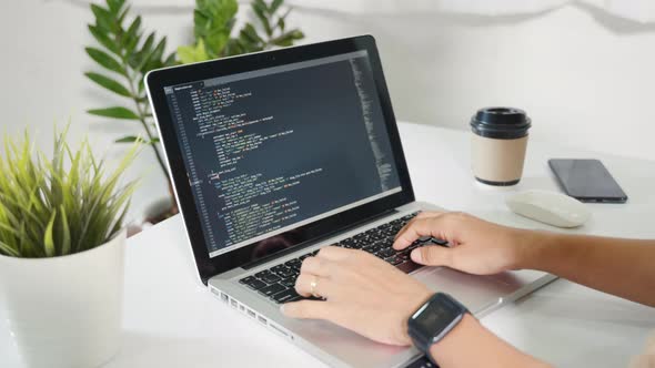 Programmer woman writing program HTML code sitting at workplace in office