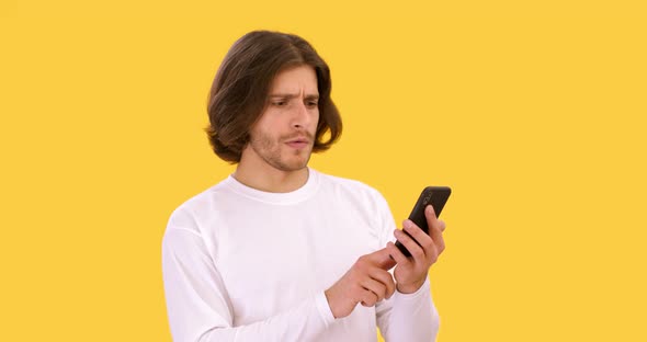 Young Serious Man Networking on Mobile Phone Reading Bad News Online and Shaking Head in Disbelief