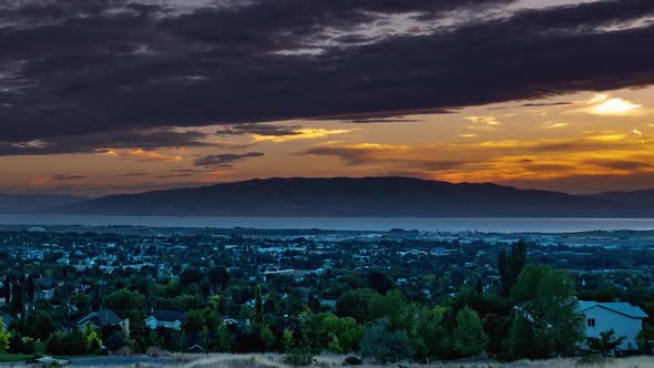 Day to night time lapse from a high view of a valley with a city in in and a lake in the background.