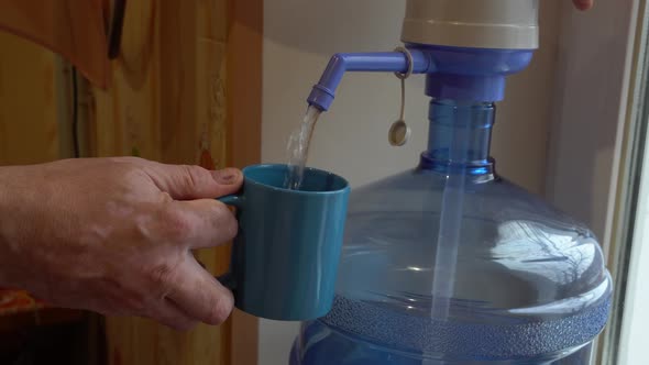 A Man Collects Filtered Water Into a Cup From a Cooler