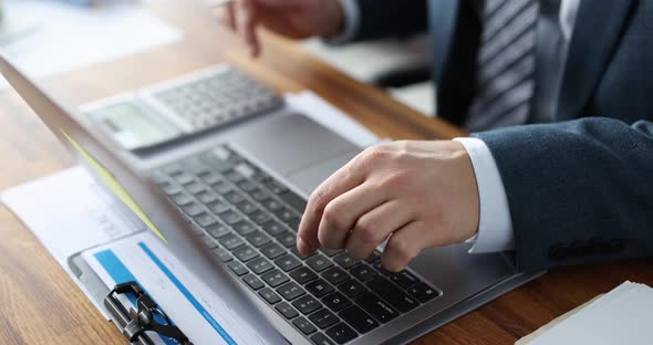 Businessman Use Laptop and Calculators While Sitting at Office Table