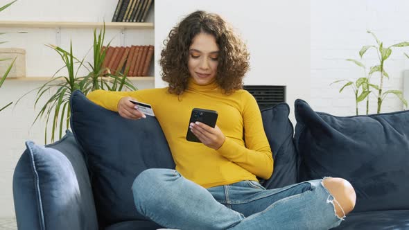 A Young Pretty Woman with Smartphone Holding a Card Making Online Payment