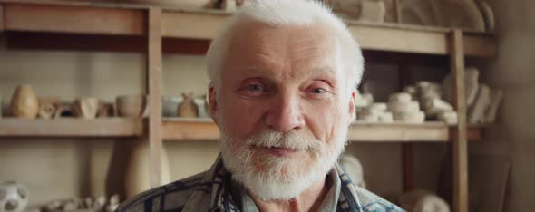 Portrait of Cheerful Elderly Potter in Workshop