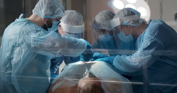 View Though Glass Door of Surgery Team Operating Patient