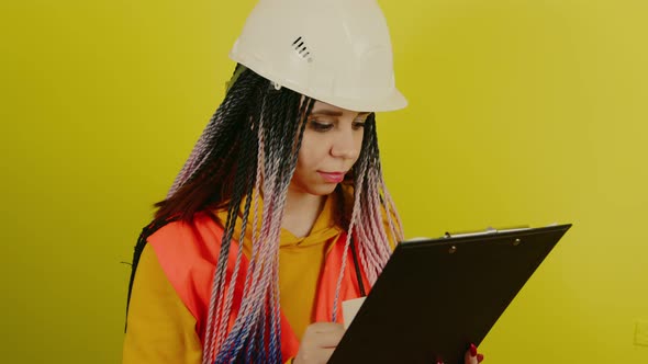 Female Construction Worker in Overalls with Clipboard