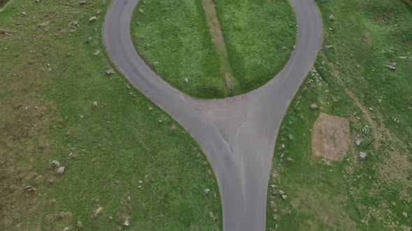 Top down birdseye aerial tracking over a an isolated country roundabout that has only two exits.