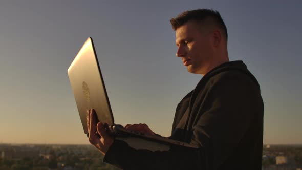 Programmer a Hacker Is on the Roof with a Laptop at Sunset Says Error Code on the Keyboard and