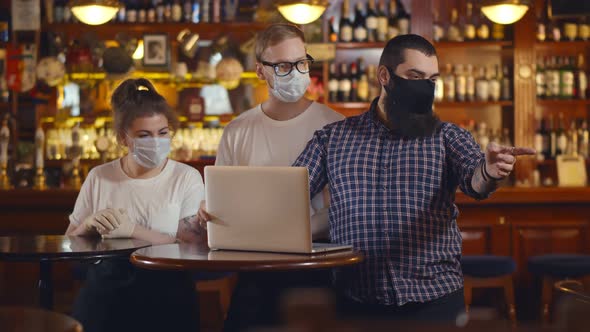 Modern Restaurant Team in Safety Mask Using Laptop Planning Redecoration