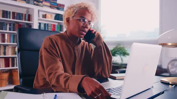 African Woman Employee in Glasses Working in Office Talking on Cellphone