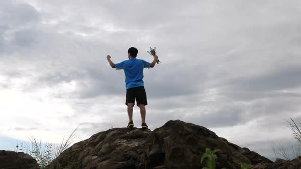 Athlete Rejoicing With Champion Cup On The Top Of Mountain