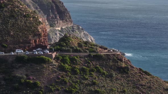 Scenic coastal road carved into mountainside next to Atlantic ocean; drone