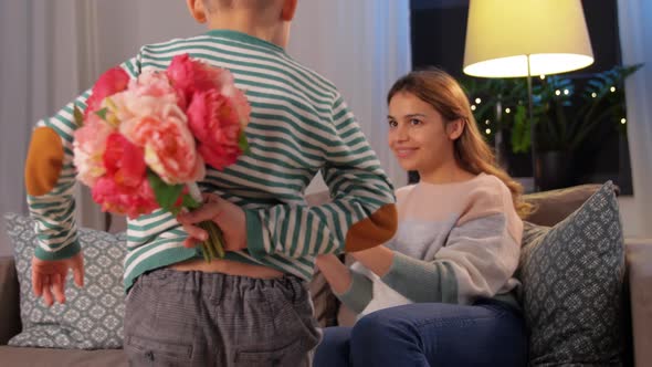 Smiling Little Son Gives Flowers To Mother at Home