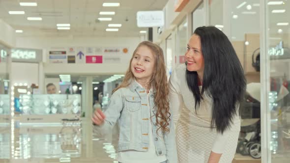 Adorable Curly Haired Little Girl Enjoying Shopping at the Mall with Her Mother