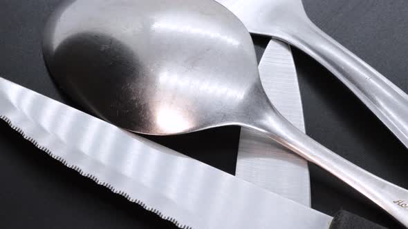 Macro shot of steel spoon on a black bacground, rotating motion. Close up view from above.