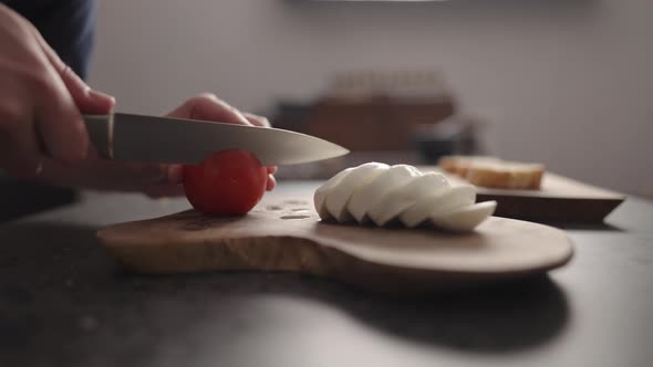 Slow Motion Man Slicing Tomatoes on Olive Wood Board