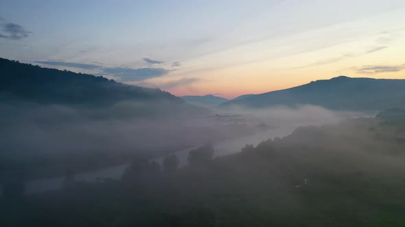 Fog over the river in the mountain valley. Landscape during sunset. View from the air.