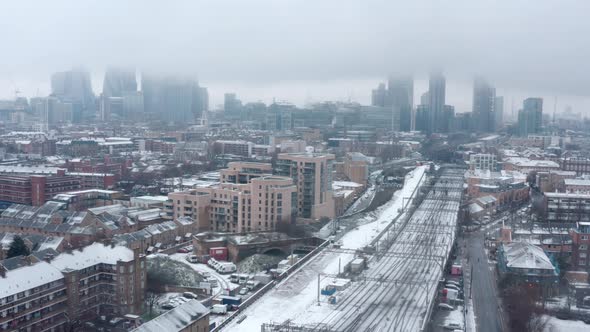 Dolly back aerial drone shot of Snow covering Central London and train tracks