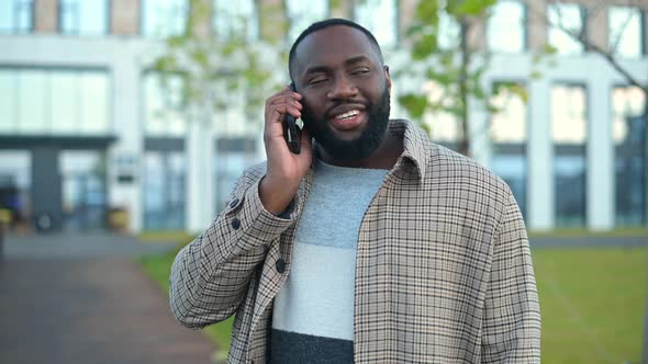 Carefree AfricanAmerican Guy Talking at Easy on the Smartphone