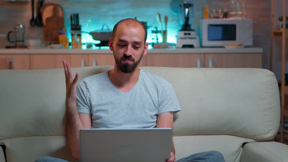 Caucasian Male Sitting on Couch in Pajamas Working on Laptop Computer