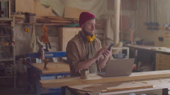 Woodworker Using Smartphone in Workshop