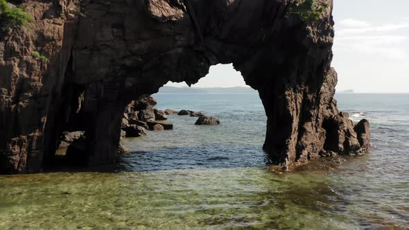 Flying a Drone Through a Natural Stone Arch on the Seashore