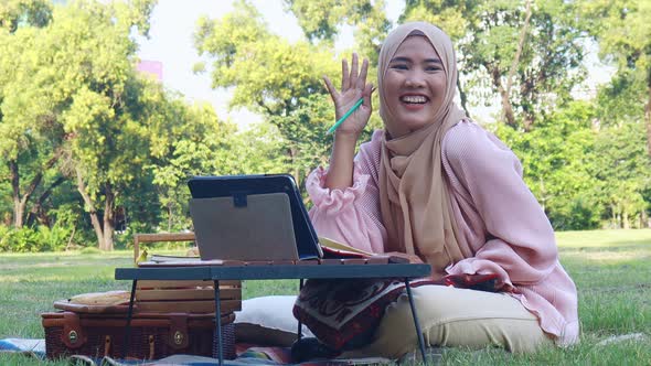 Beautiful Muslim girl sitting happily in the park. 