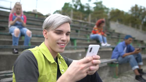 Happy College Student Typing Smartphone Message Sitting Outdoors, Internet