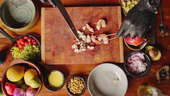 Preparation of ceviche salad - table top view of a professional chef cutting the prawn into bit size