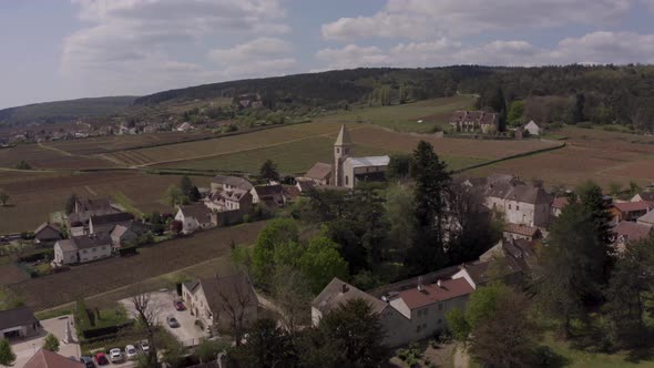 Beautiful aerial of historic church in middle of vineyards in Burgundy, France. Countryside village
