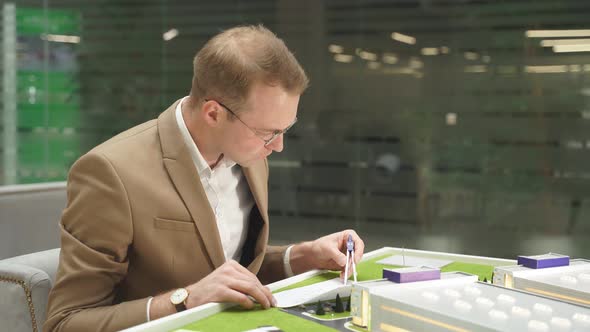 Male Architect with Plan on Paper, Stationery and 3d Building Model