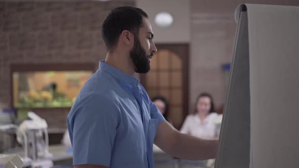 Close-up of Confident Middle Eastern Lecturer Gesturing and Talking To Caucasian Students in Dental