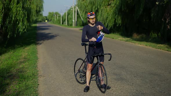 Sportsman Putting on His Helmet on a Bicycle Full Length